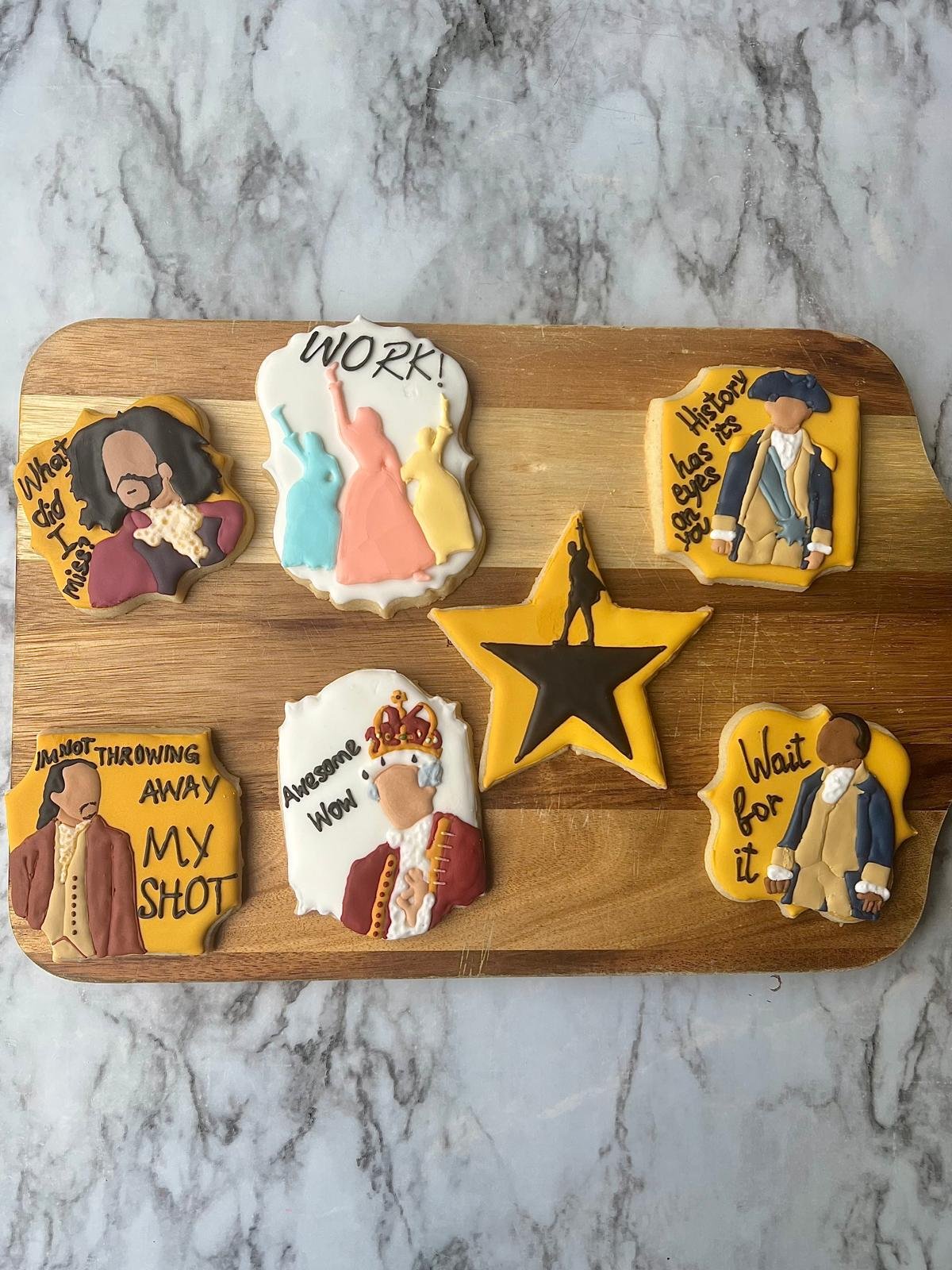 Hamilton-themed custom decorated sugar cookie set on a wooden board