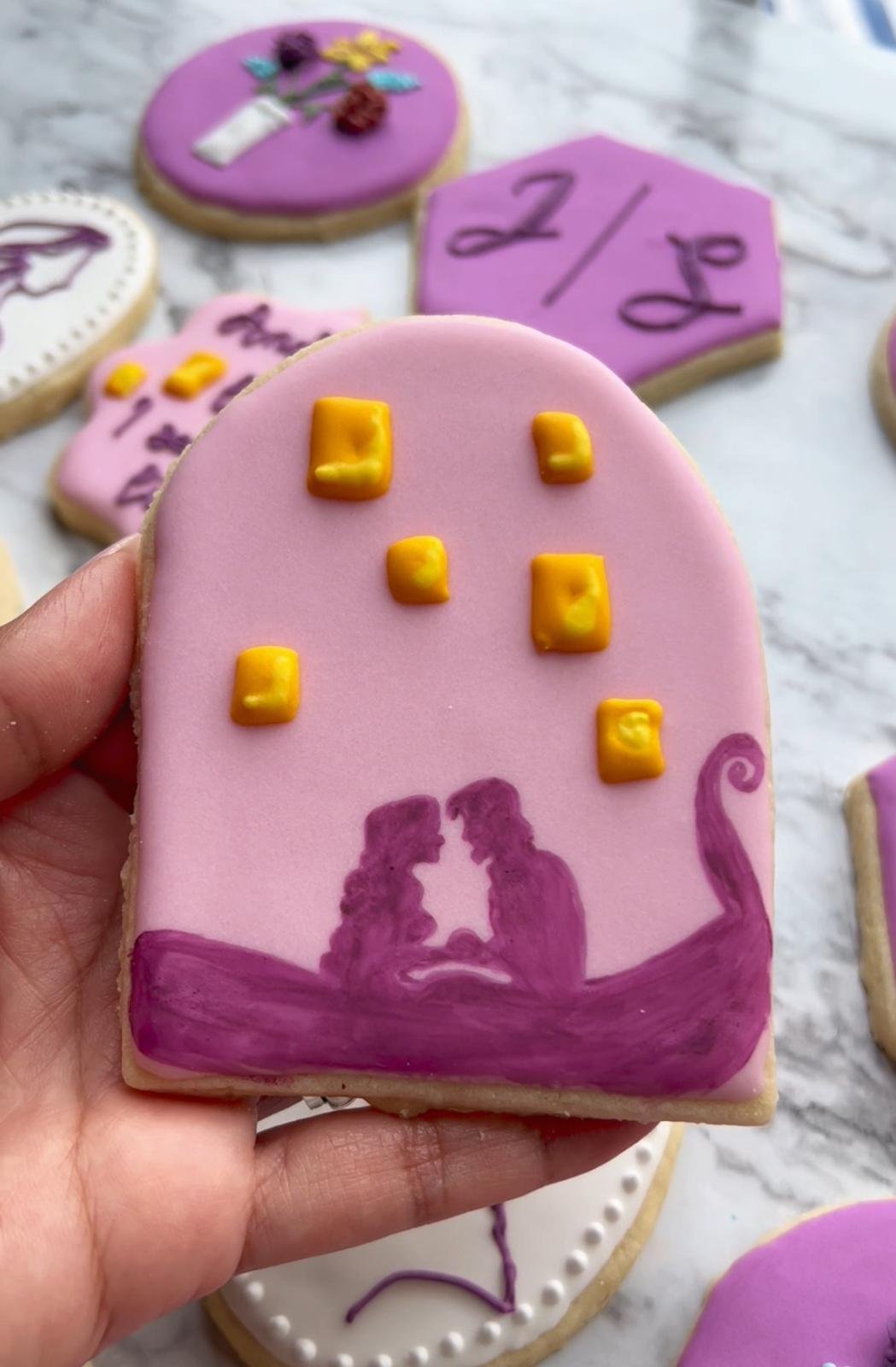 Single hand-decorated sugar cookie held in hand