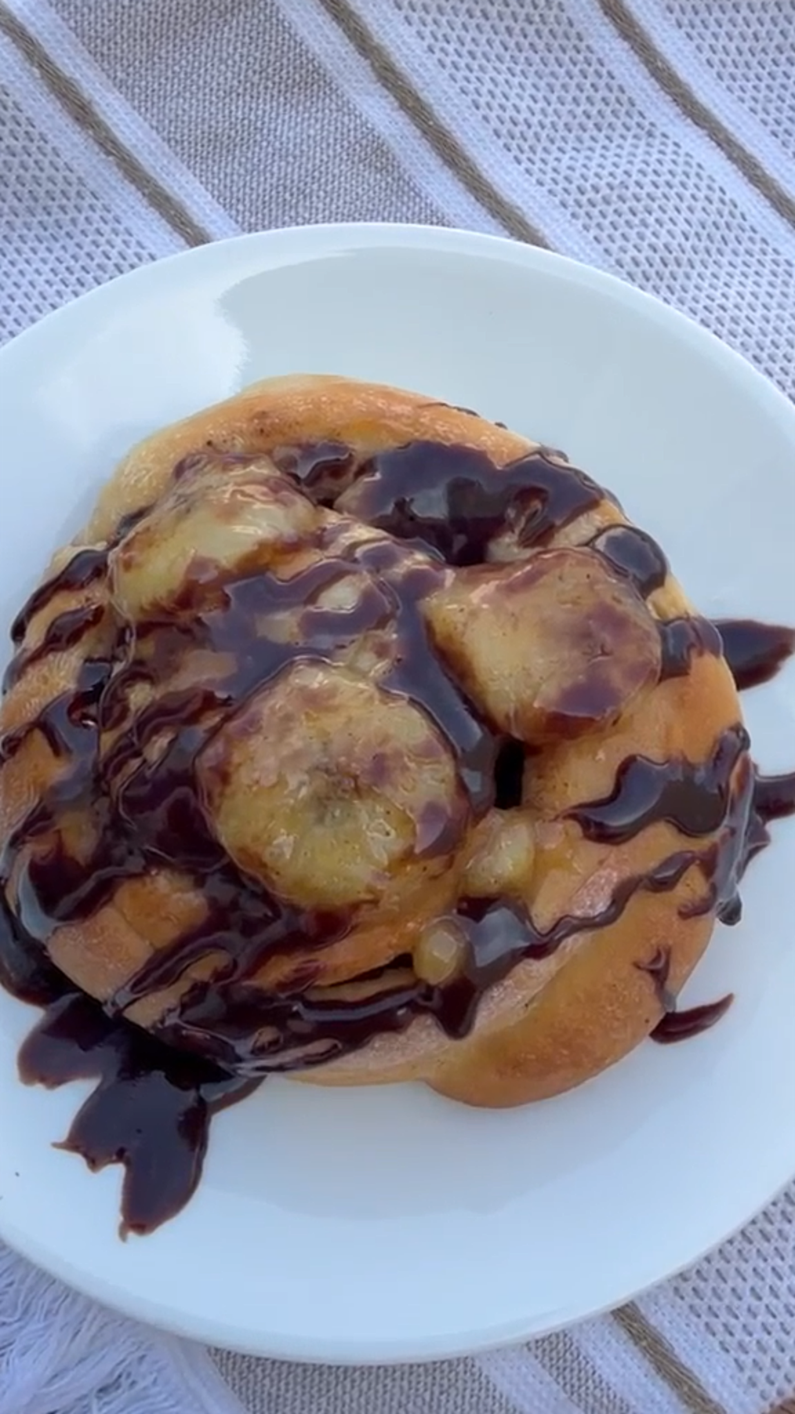 Choco Banana cinnamon roll with chocolate cream cheese frosting, chocolate drizzle, and banana slices