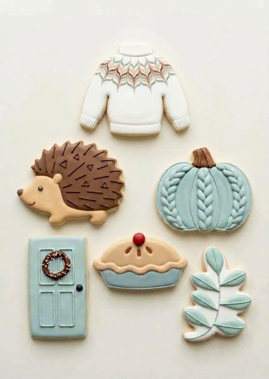 Six Warm and Fuzzy themed sugar cookies: sweater, hedgehog, knit pumpkin, door with wreath, pie, and leafy sprig